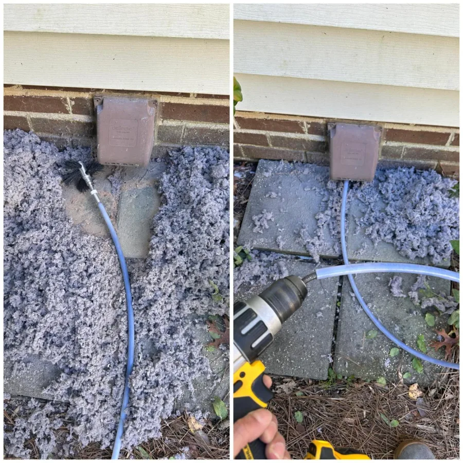 Technician clearing a blocked dryer vent at an exterior wall cap, with the removed lint on the ground
