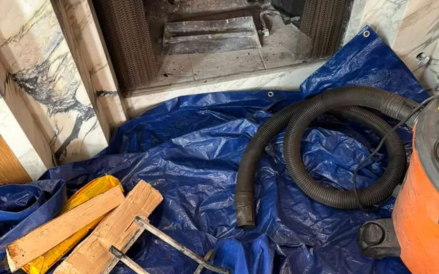 A technician rotary-rod sweeping a chimney flue, with creosote collected below in HEPA containment